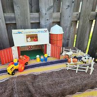 Full farm set outdoors showing barn, silo, animals, tractor with wagon, 3 peg people and fencing.