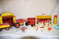 Full lot overview showing large yellow barn, small red barn, red tractor and trailer, metal implements, plastic animals and silo