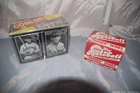 Photo showing two boxes of baseball cards: one black sealed Conlon Collection box and one red and white 1989 Topps 'Traded' Series box.