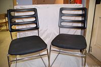 Two black Chromecraft chairs with chrome tubular frames, side by side showing front and side view.
