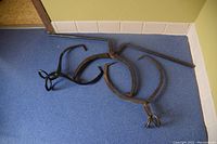 Overview of three iron ice tools on blue floor: two ice picks and one ice auger.