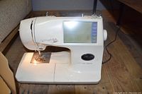 Side angle view of the Brother PC-8500 sewing machine powered on, showing the LCD screen and machine controls.