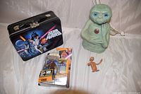 Photo displaying all items in the lot together including ET night light, Star Wars lunchbox, Mace Windu action figure in box, and small ET figurine