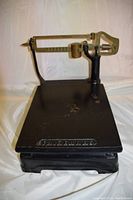 Full view of antique Fairbanks mechanical counter scale showing black cast iron base with wear and Fairbanks name embossed on front edge of platform.