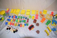 Wide view of all Fisher Price Playskool toy figures and accessories spread on white backdrop displaying variety of chairs, people, game boards, animals, and other play accessories