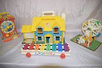Wide shot showing the three Fisher Price vintage toys including Play Family House, clock toy, and merry-go-round toy.