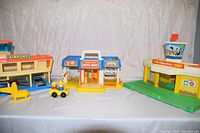 Full view of three Fisher-Price vintage playsets: airport, Little Mart store, gas station, with helicopter and car toys.
