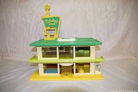 Front view of the Playskool Holiday Inn toy showing the green roof, yellow base, and lobby entrance with Holiday Inn sign.
