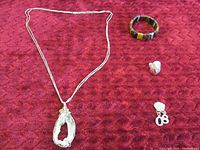 Sterling silver necklace, bracelet, ring, and earrings on dark red textured fabric