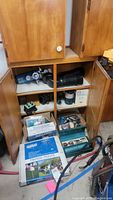 Wooden cabinet with assorted equipment and boxes, showing welding tools, hoses, and Winegard mount box on lower shelf.