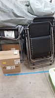 Stacked outdoor chairs next to boxed air mattress, showing the chairs' size and form