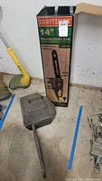 Overall view of the Craftsman 14-inch electric chain saw original box and carrying case placed on the ground.
