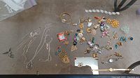 Overview of costume jewelry including clip-on earrings, brooches, necklaces, and watches spread on a surface