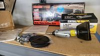 Craftsman Twin Cutter Saw in original box, Central Pneumatic air cutter with accessories on table