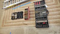 Wide shot of six drill bit sets in different organizer cases, showing layout and variety