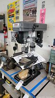 Full image of the Central Machinery bench drill press with gloves and manual on base.