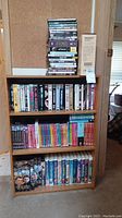 Stack of DVDs plus VHS tapes organized on wooden shelves