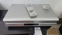 Front view of Toshiba SD-V392 combo unit including remote control placed on top showing buttons and disc slot