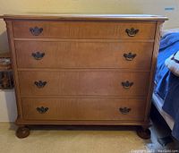 Front view showing four drawers with brass handles and the wooden finish.