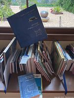 Image showing multiple books on architecture arranged standing on a windowsill, one book on top is titled 'Architecture in America A Battle of Styles'.
