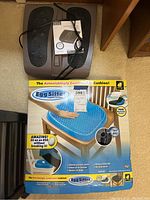 Photo showing both the Egg Sitter gel seat cushion box and Homedics Deep Kneading Shiatsu foot massager on the floor.