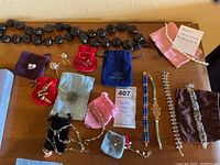 Assorted jewelry laid out showing black bead necklace and multiple pouches