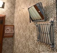 Vintage extendable rectangular bathroom mirror mounted on wall showing accordion arm.
