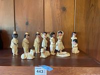 Front view of whole nativity set showing all human and animal figurines arranged in a row on wooden shelf.