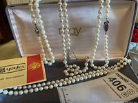 Four pearl necklaces displayed in box with Majorica Certificate of Authenticity and auction tag