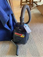 Front view of blue Sharp vacuum cleaner showing hose, base, and motor housing with peak horsepower label.