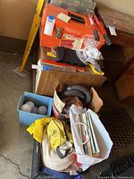 Full view of the lot including orange tool box, bolt cutters, shop vac hose, light bulbs, and assorted tools