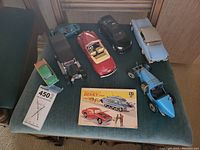 Seven Dinky Toys model cars displayed on teal chair with original Dinky Toys leaflet, auction tag included.