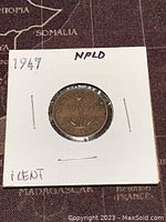 Reverse side of 1947 Newfoundland one cent coin showing maple leaf design and date within holder.