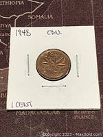 Front side showing the reverse of the 1 cent coin with maple leaves and date 1948