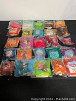 Set of 25 colorful McDonald's toys individually bagged, laid out in rows, showing diverse character designs and colors representing the whole lot