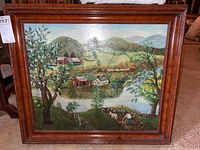 Full view of the framed landscape painting depicting rural hills, houses, and river.