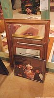 Six stacked framed cowboy photos and prints with visible wood and black frames.