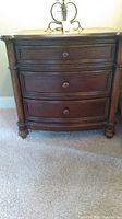 Front view of dark wood nightstand with three drawers