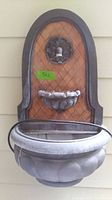 Front view of wall mounted garden fountain showing arched back panel with diamond pattern and two basins.