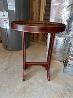 Full view of the decorative wood table showing oval top, legs, and base.