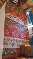 Full view of rug laid on floor showing overall geometric southwest pattern and color palette.