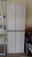 Front view of beige plastic utility cabinet with four panel doors.