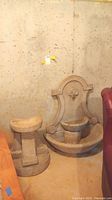 Both fountain top and pedestal base side by side against concrete wall
