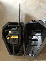 Top view of the Eager Beaver gas chainsaw inside the plastic carrying case, showing the full tool and part of the case interior.