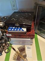 Stacked boxes of various cutlery sets and loose wrapped knives in foreground