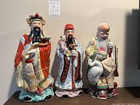 Set of three Asian porcelain figurines displayed together, showing overall size and detail.