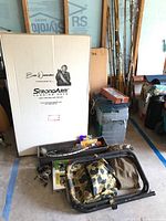 Full lot overview showing fishing rods, landing net box, tackle box, folding stool, reels, and fishing accessories arranged on floor.