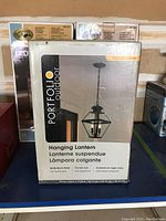 Boxed Portfolio Outdoor Castle Creek Hanging Lantern showing front packaging with product image and features.