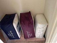 Three comforters packaged in bags, two in branded Weatherproof Vintage Home bags and one wrapped in white plastic.
