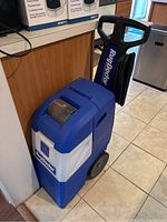 Front angled view of blue and white Rug Doctor unit showing overall structure and housing